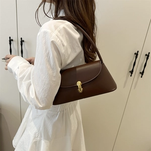 Retro dark brown leather baguette bag with gold U-buckle worn on a white summer dress