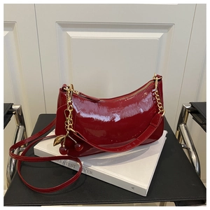 Détail du sac en cuir verni rouge avec chaîne dorée et charm cerise décoratif