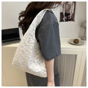Detailed shot of white floral lace shoulder bag featuring intricate embroidery textures