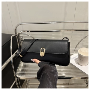 Détail du sac bandoulière en cuir noir brillant avec un fermoir rotatif ovale doré chic