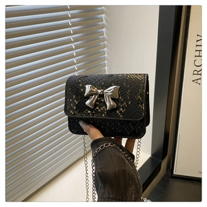 Close-up of black snakeskin texture mini bag with silver metal bow and chain strap