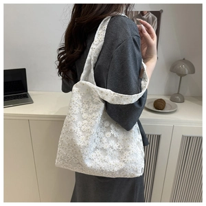 Detailed view of elegant white floral lace tote bag on a minimalist desk surface