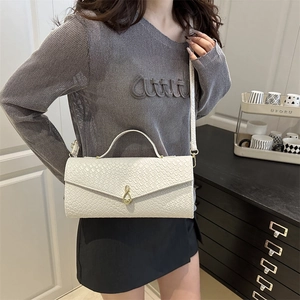 Sac baguette blanc à motif crocodile avec fermoir doré porté par le mannequin