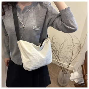 Close-up of minimalist white waterproof fabric bag with black zipper and wide shoulder strap