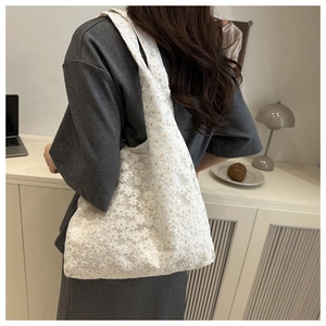 Detail of white lace crochet pattern on a floral tote bag worn over the shoulder