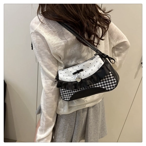 Detail of coquette style shoulder bag showing black ruffles and heart metal pendant