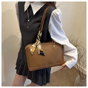 Close-up of brown leather tote bag with silk scarf detail on handle and fine stitching