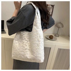 Detailed view of white floral lace embroidery on a soft shoulder tote bag for summer