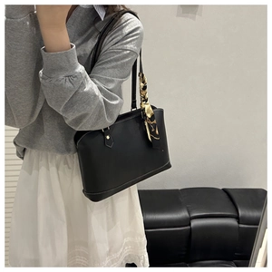 Shoulder shot of black tote bag with printed silk scarf and gold hardware detail