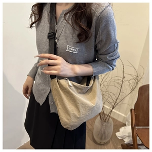 Detail of a khaki nylon crescent crossbody bag with adjustable wide black strap
