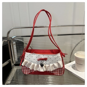 Detail of sweet-style shoulder bag with ruffles, red bow, and heart pendant on a chair