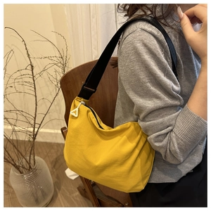 Detail of bright yellow crossbody bag with black strap and unique white triangle zipper