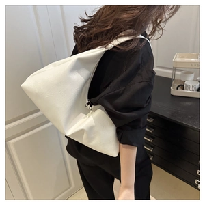 Detail of white leather tote bag with soft texture and stylish pleated design on shoulder