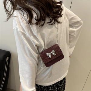 Burgundy snakeskin texture mini crossbody bag with silver bow accent and metal chain strap
