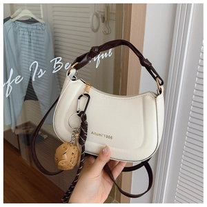 Close-up of cream white crescent shoulder bag with knot handle and gold Aitumi logo