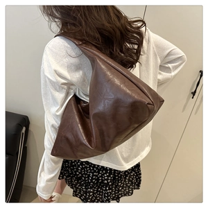 Deep brown soft leather tote bag showing large capacity and minimalist design on model
