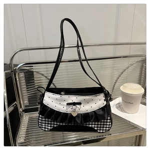 Detail of a chic bow handbag with gingham pattern, frill accents and a heart charm