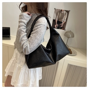 Close-up of black pleated leather texture on a spacious minimalist shoulder bag