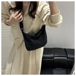 Detailed view of black nylon half-moon crossbody bag with adjustable wide strap on model