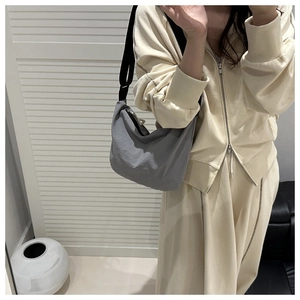 Detailed view of the gray nylon crescent bag with wide black strap on model