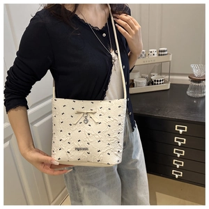 Detail of cream white bucket bag with jacquard texture and bow heart charm detail