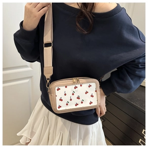 Detail of crossbody bag with red cherry print and adjustable wide fabric strap