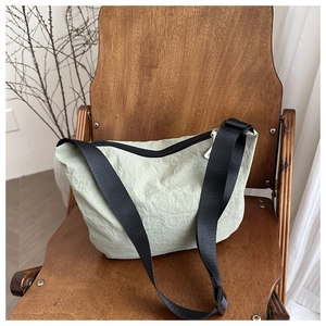 Detail of sage green hobo bag with pleated texture and adjustable black strap