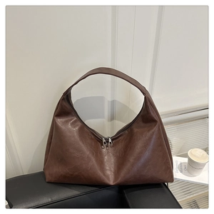 Detail of dark brown tote bag featuring vintage leather texture and dual zipper design