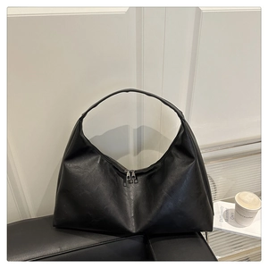 Close-up of minimalist black matte leather hobo tote bag with silver dual zipper hardware