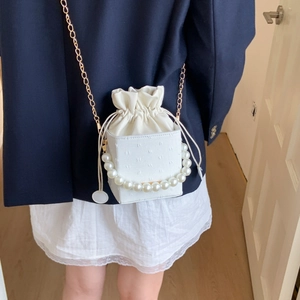 White faux leather crossbody bag with pearl handle and embossed texture on model