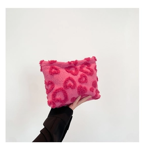 Detail of pink plush clutch bag with 3D fuzzy heart patterns and soft texture