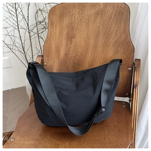 Close-up of black nylon hobo bag with adjustable strap on a vintage wooden chair