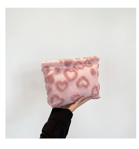 Detail of pink plush clutch bag with 3D heart pattern and soft faux shearling texture