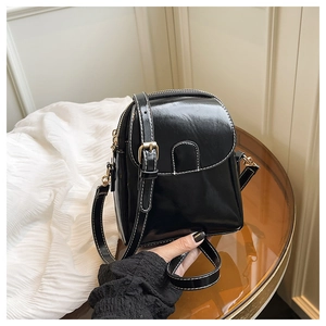 Détail du mini sac bandoulière en similicuir noir brillant avec surpiqûres blanches