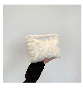 Detail of white plush handbag featuring 3D heart-shaped embossed texture and soft fabric