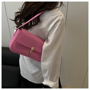 Close-up of stylish pink square shoulder bag with gold metal buckle on model