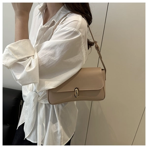 Detail view of beige leather shoulder bag featuring a gold U-shaped metal twist lock