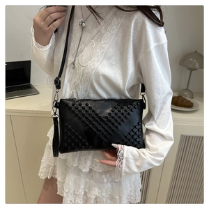 Detail of black leather square bag with V-shaped stud patterns and metallic zipper