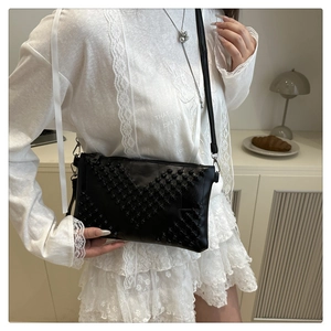 Close-up of black crossbody bag featuring a beaded star design on white lace outfit
