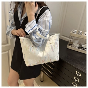 Close-up of white tote bag with wave embroidery worn by model in striped shirt