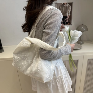 Grand sac cabas minimaliste en dentelle blanche avec broderie florale porté par un mannequin