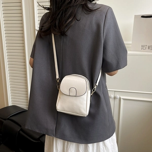 Sac à bandoulière blanc minimaliste avec zips dorés porté par un mannequin chic