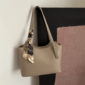 Detail of khaki leather tote bag featuring elegant printed silk scarf handle and gold buckle