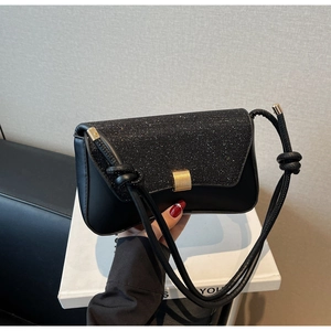 Gros plan sur le rabat à paillettes noires du sac bandoulière avec boucle dorée élégante