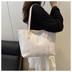 Detail of white tote bag with colorful wave embroidery and metallic rivet hardware