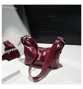Detail of burgundy glossy patent leather bag with wide eyelet strap and metallic buckle