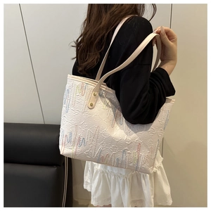 Detail of off-white tote bag with wave embroidery and gold rivets on slim shoulder straps