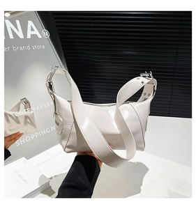 Detail of white glossy patent leather hobo bag with adjustable silver metal buckle strap