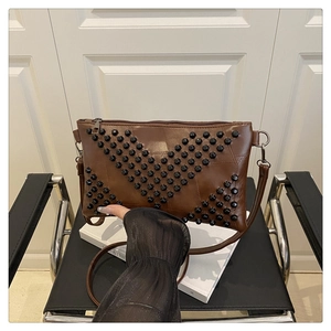 Detail of dark brown faux leather crossbody bag with geometric black rivet studs