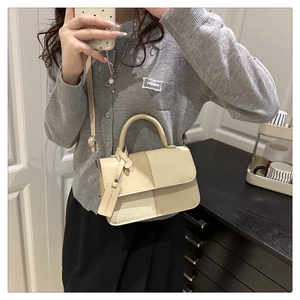 Détail du sac beige avec surpiqûres géométriques en maille et étiquette de mode